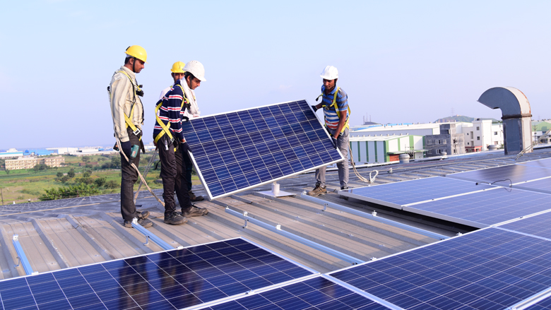 Rooftop solar panels on a home in Goa with technician inspecting inverter.