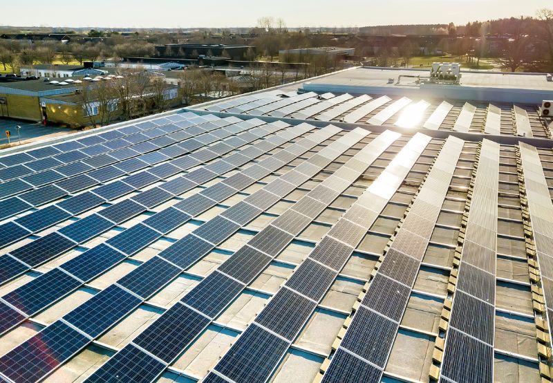 Rooftop solar panels under a bright sky, mounted on a flat roof.